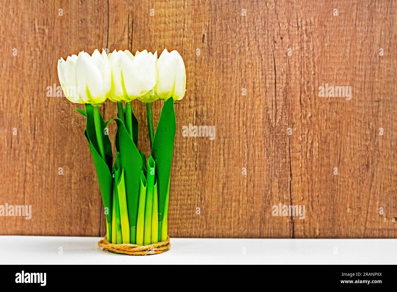 bouquet di tulipani bianchi su un tavolo vicino a una copertura di legno. Atmosfera natalizia Foto Stock