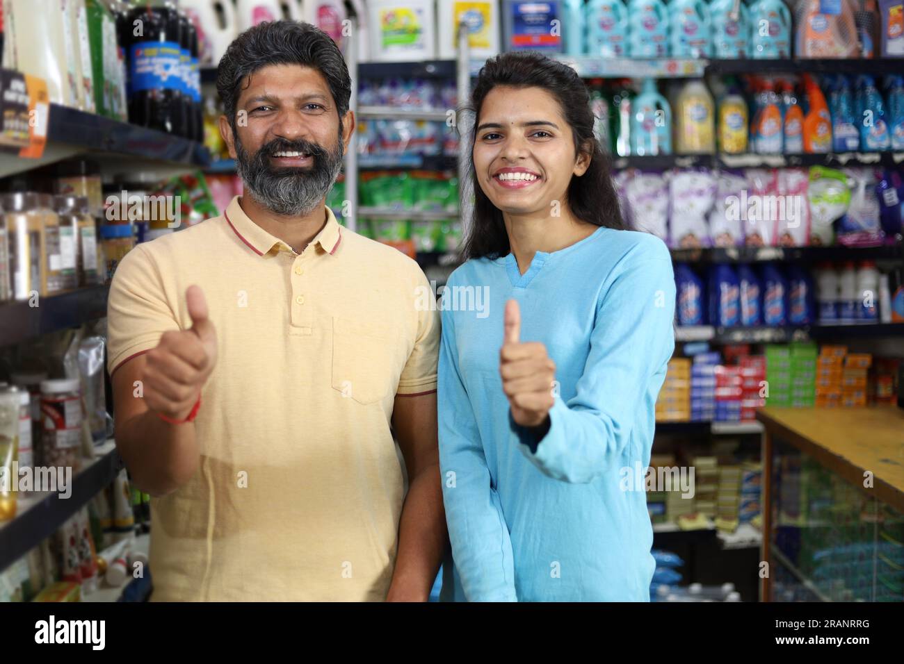 Felice coppia indiana che si diverte ad acquistare in un negozio di alimentari. Comprare della spesa per la casa al supermercato. Alzare il pollice. Clienti soddisfatti e soddisfatti Foto Stock