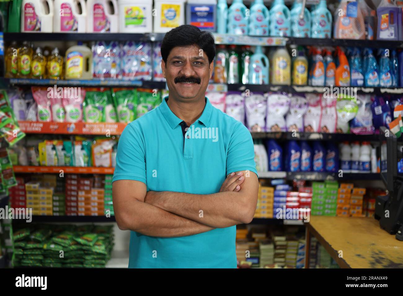 Ritratto di un uomo indiano felice e sorridente che acquista in un negozio di alimentari. Comprare della spesa per casa in un supermercato. Uomo sicuro e in forma nei baffi. Foto Stock