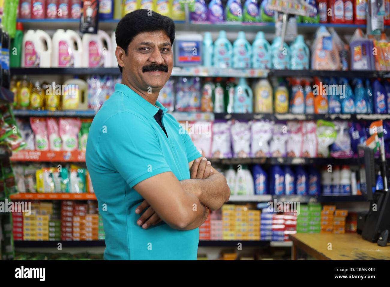 Ritratto di un uomo indiano felice e sorridente che acquista in un negozio di alimentari. Comprare della spesa per casa in un supermercato. Uomo sicuro e in forma nei baffi. Foto Stock