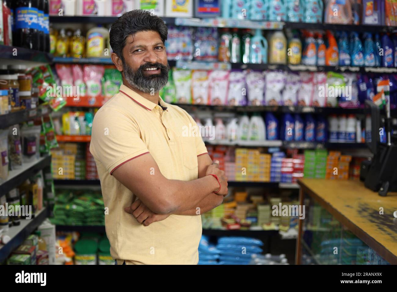 Bellissimo ritratto di un uomo barbuto bello e sorridente che fa shopping e posa nell'ipermercato. Mini centro commerciale locale sorrisi felici di clienti soddisfatti. Foto Stock