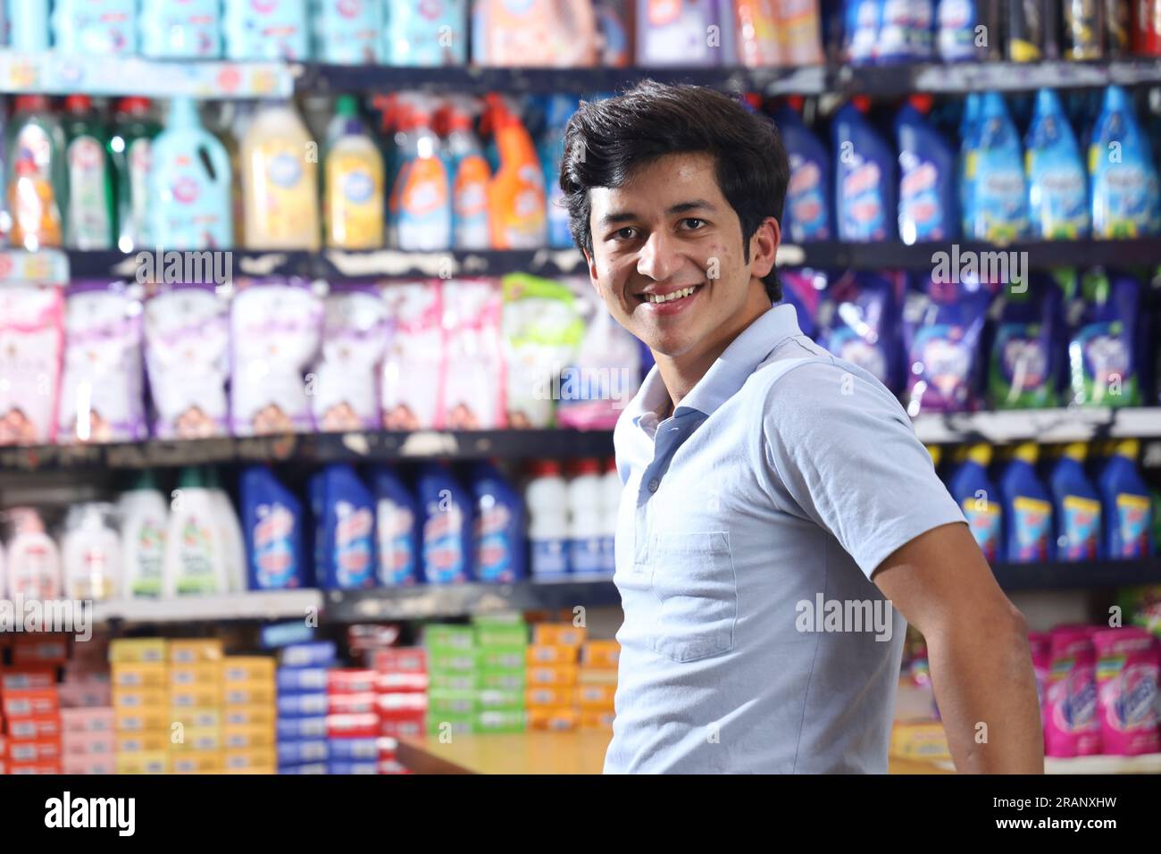 Bellissimo ritratto di bel giovane indiano sorridente che fa shopping e posa nell'ipermercato. Mini centro commerciale locale sorrisi felici di clienti soddisfatti. Foto Stock