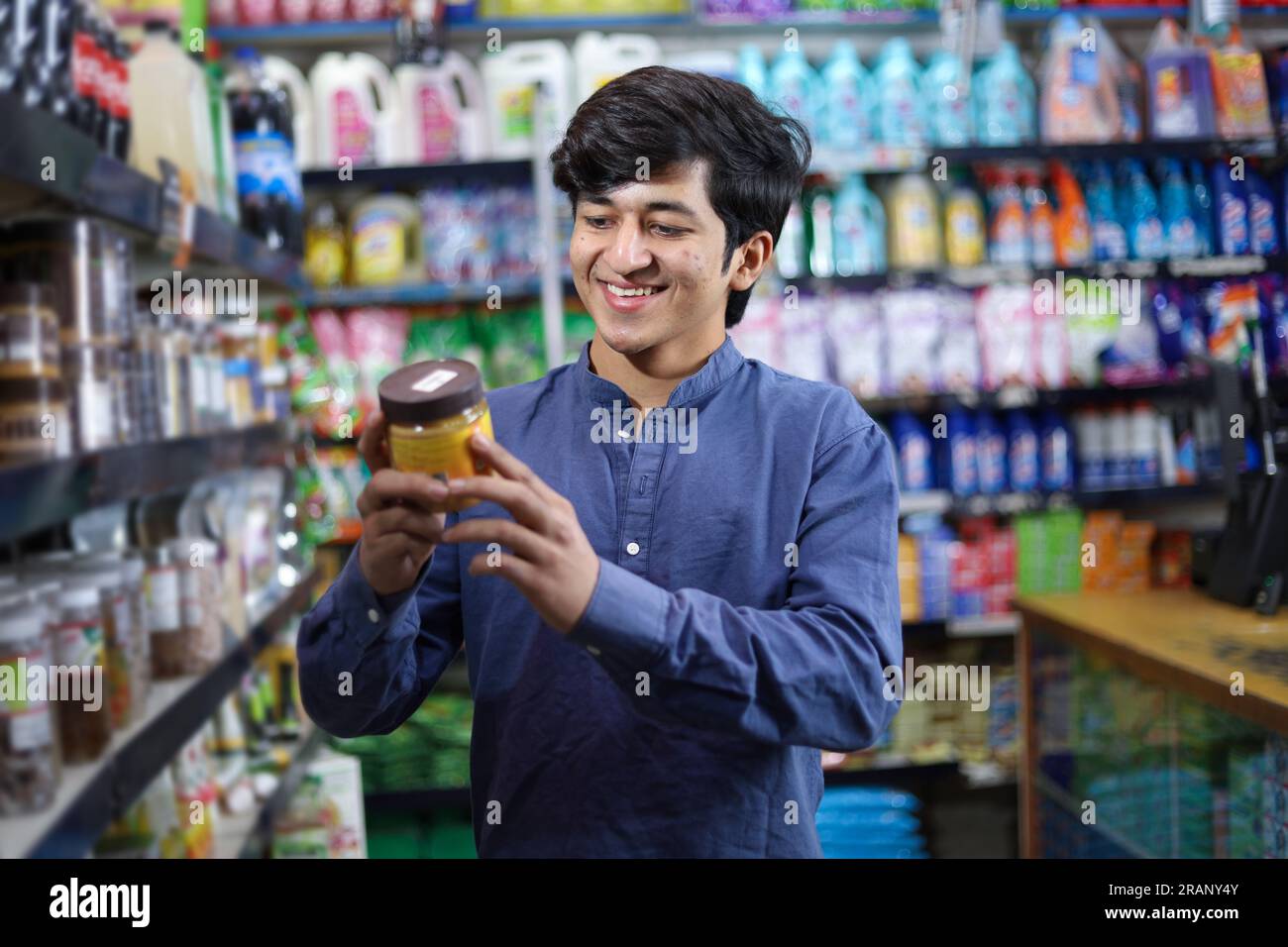 Uomo felice che acquista in un negozio di alimentari. Comprare della spesa per casa in un supermercato. esame di un prodotto Foto Stock