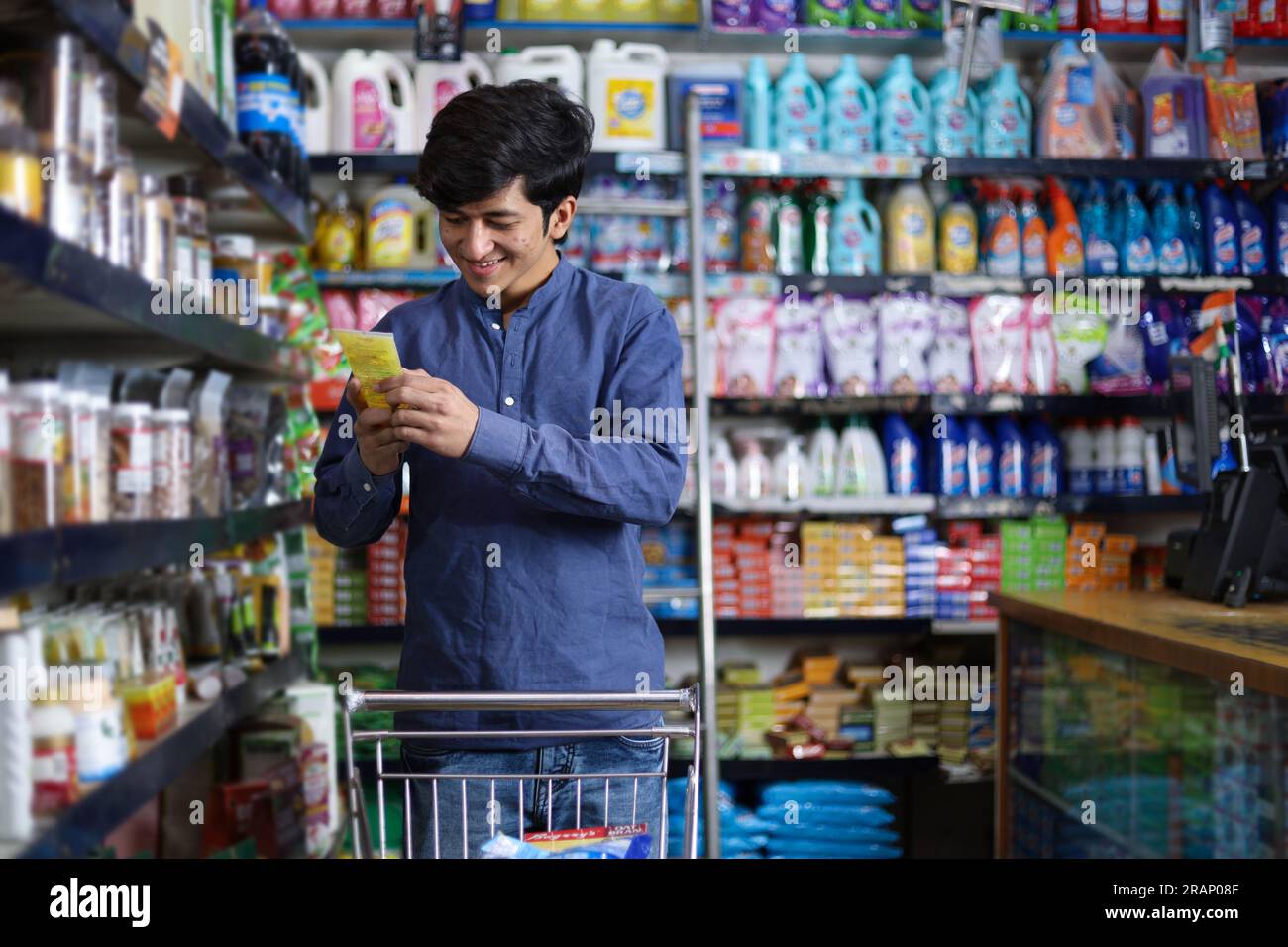 Uomo felice che acquista in un negozio di alimentari. Comprare della spesa per casa in un supermercato. esame di un prodotto Foto Stock