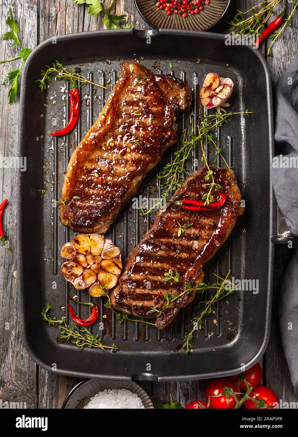 Bistecca di striploin alla griglia con spezie ed erbe sulla teglia di ferro. La bistecca di strip, chiamata anche striscia di New York. Foto Stock