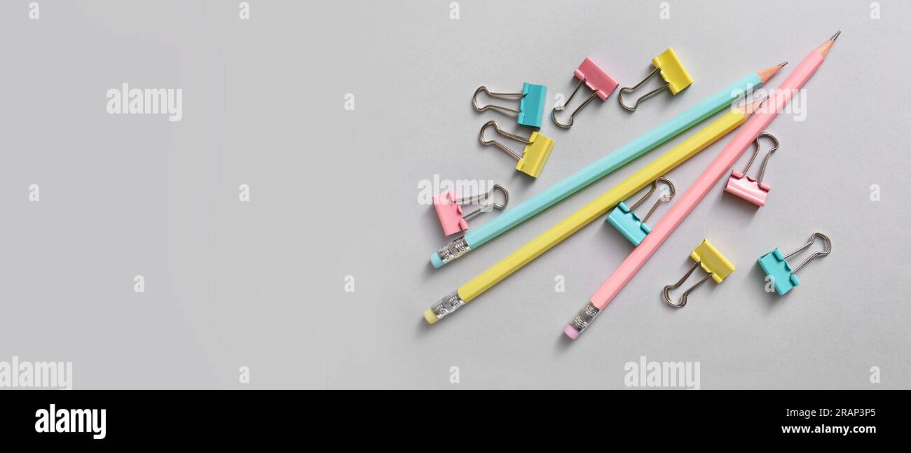 Clip colorate e matite su sfondo grigio con spazio per il testo Foto Stock
