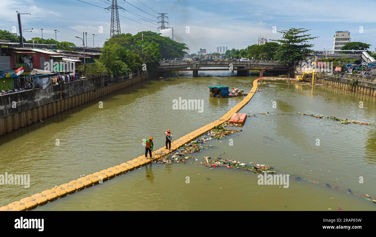 Giacarta, Indonesia - 11 ottobre 2022: I lavoratori di una trappola galleggiante rimuovono il fiume dai detriti. Giacarta, Indonesia. Foto Stock