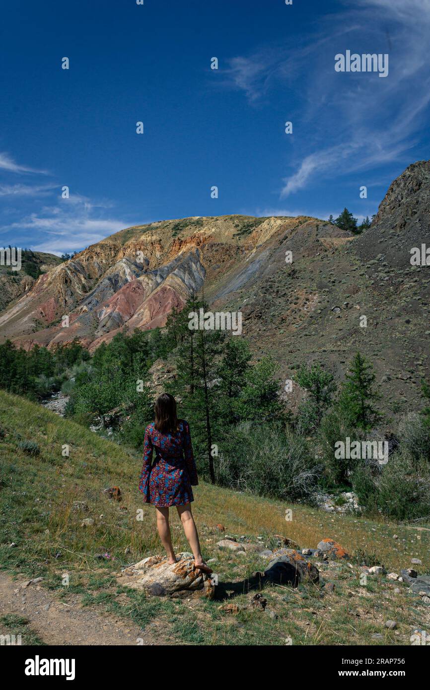 Una giovane donna con un abito corto si erge sullo sfondo del famoso monumento storico Altai Mars nel canyon. concetto di viaggio estivo Foto Stock