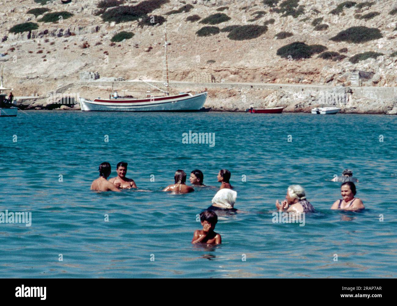 Immagine scansionata della popolazione locale che fa il bagno a Pserimoss in Grecia. Le donne anziane sono completamente vestite, mentre i membri più giovani adottano atteggiamenti occidentali; solo di Foto Stock