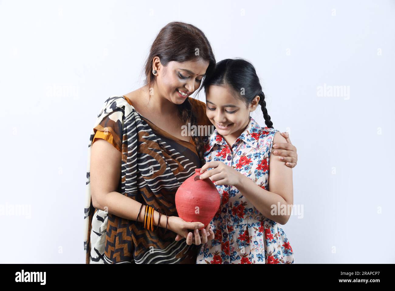 Felice famiglia di donne indiane rurali che risparmiano soldi per il futuro in salvadanaio. Aspirante signora che mostra il concetto di risparmio. Foto Stock