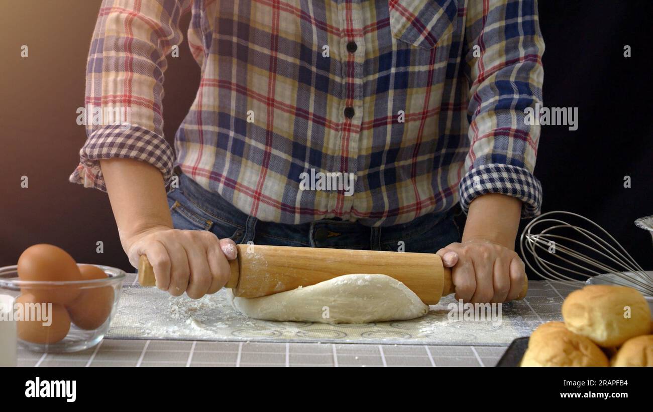 Pane artigianale lavorato con l'impasto. Farina spolverata sull'impasto, impasto del pane fatto a mano per arrotolare e impastare in cucina con strumenti per la panetteria Foto Stock
