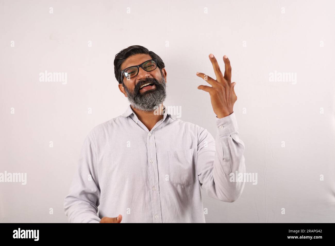 Ritratto di un uomo barbato indiano che indossa una camicia. Espressioni funky che ritraggono il senso di realizzazione e di realizzazione. Sentirsi fieri di eseguire le cose. Foto Stock