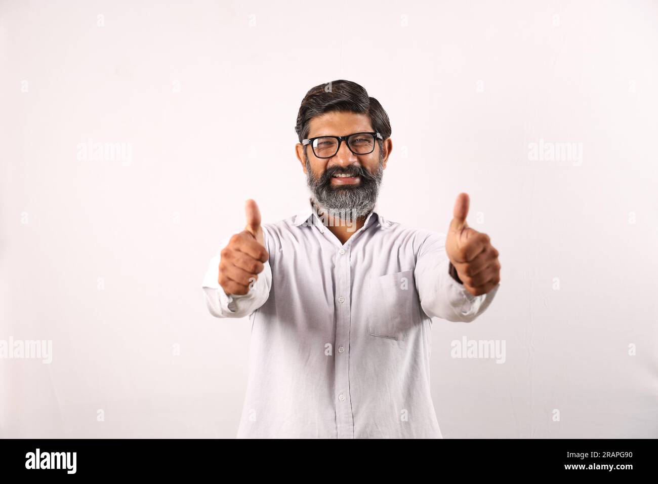 Ritratto di un uomo barbuto indiano che indossa una camicia. Espressioni funky senso di realizzazione e realizzazione. Pollice in alto. Strategia vincente. Foto Stock