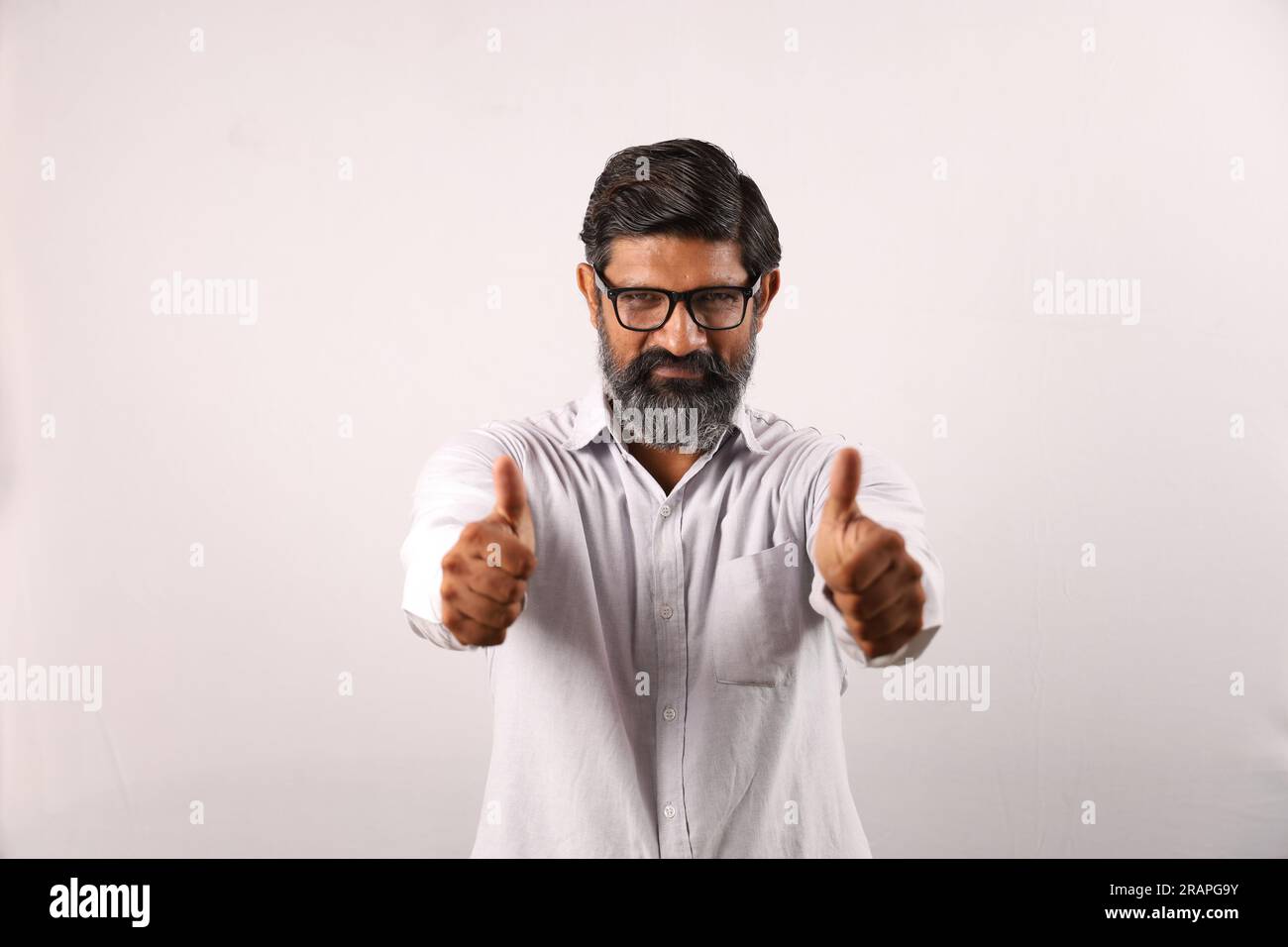 Ritratto di un uomo barbuto indiano che indossa una camicia. Espressioni funky senso di realizzazione e realizzazione. Pollice in alto. Strategia vincente. Foto Stock