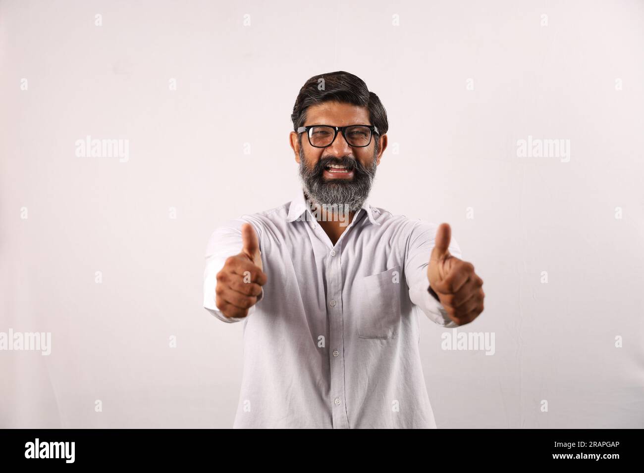 Ritratto di un uomo barbuto indiano che indossa una camicia. Espressioni funky senso di realizzazione e realizzazione. Pollice in alto. Strategia vincente. Foto Stock