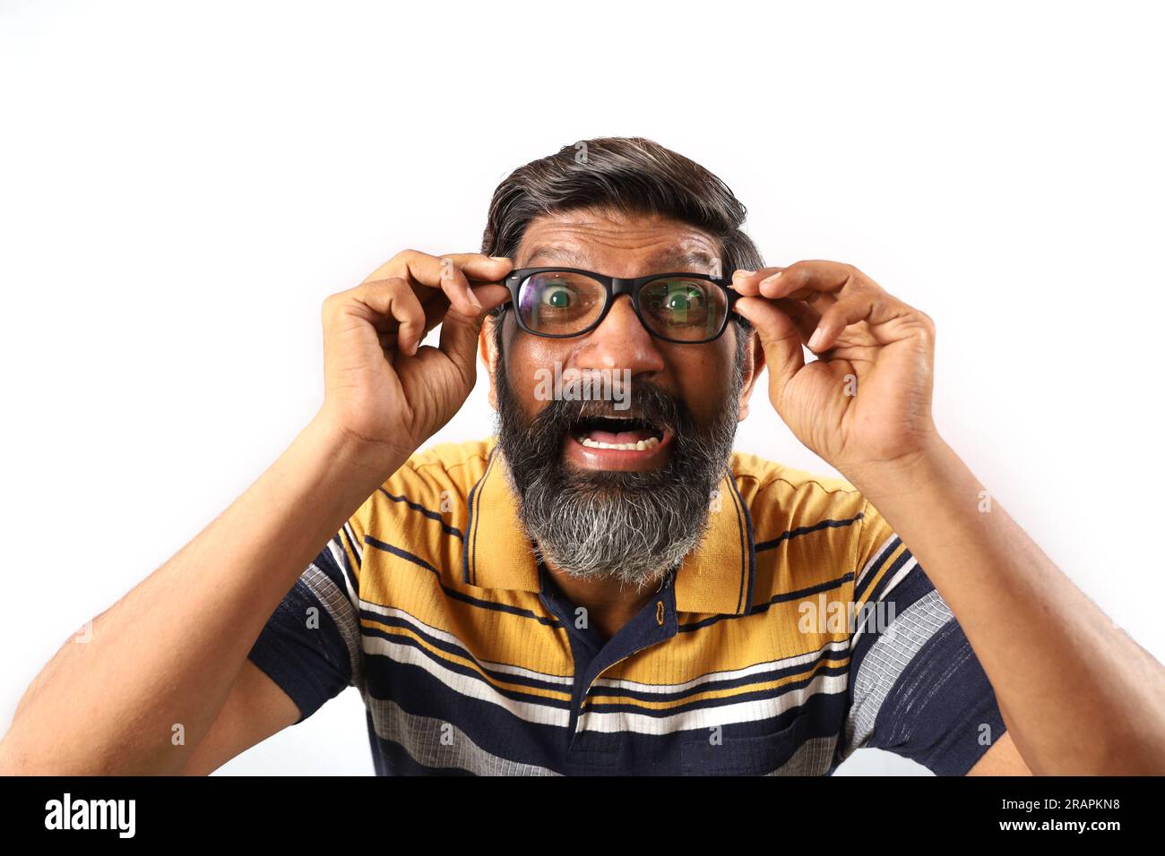 Ritratto di un uomo indiano barbuto che indossa occhiali e t shirt. Espressioni funky volto distorto. Uomo sbalordito che mostra vari stati d animo di stravagante personalita Foto stock Alamy