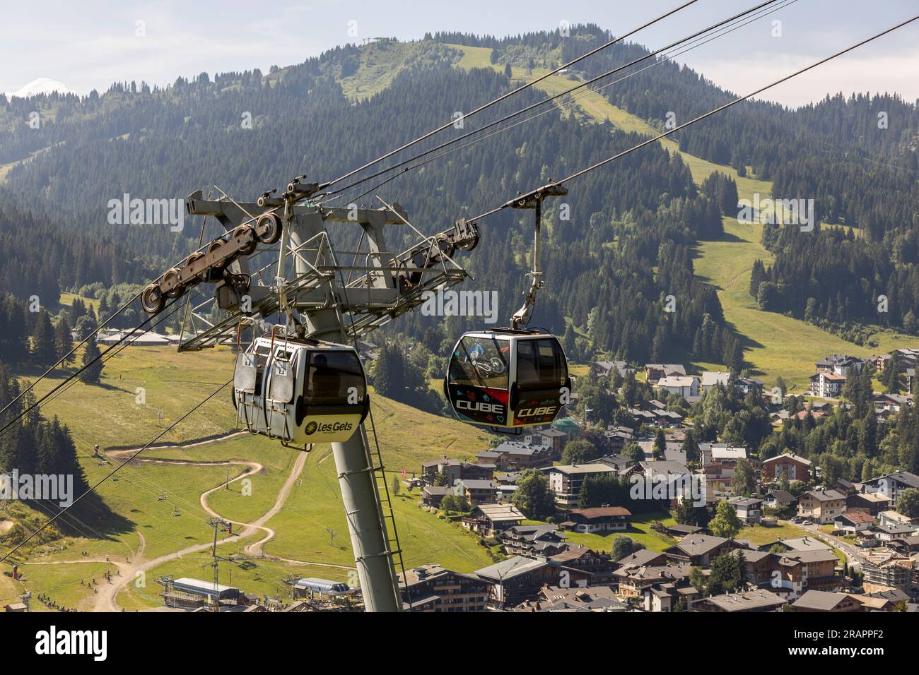Funivia con nelle alpi francesi che si librano in aria con paesaggi montuosi fuoristrada sullo sfondo Foto Stock