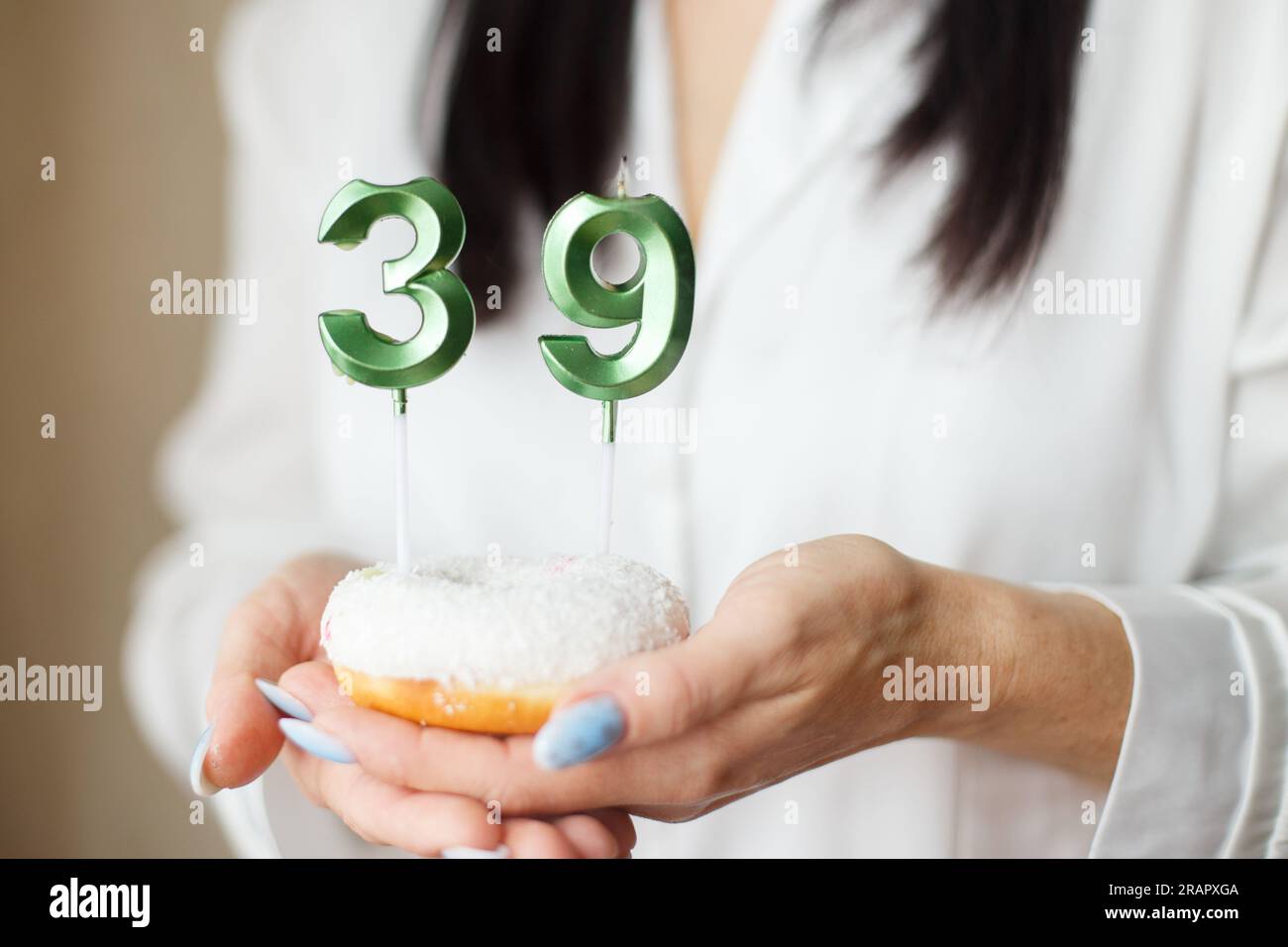 donna che tiene una torta con le candele numero 39. Foto Stock