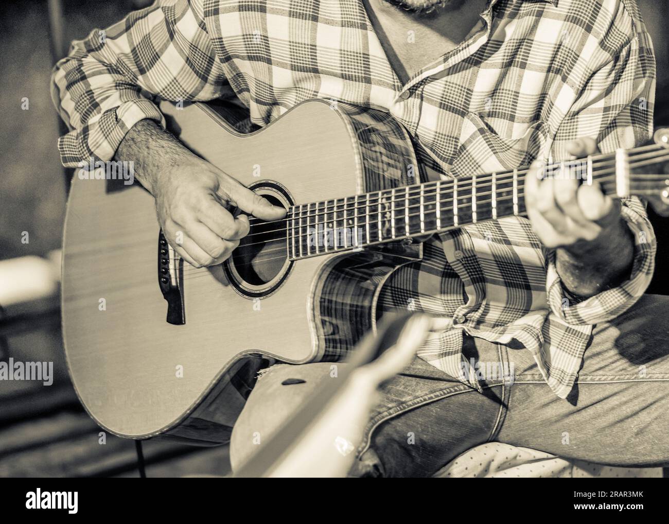 Primo piano di un chitarrista durante una performance sul palco che suona uno strumento folk. Foto Stock