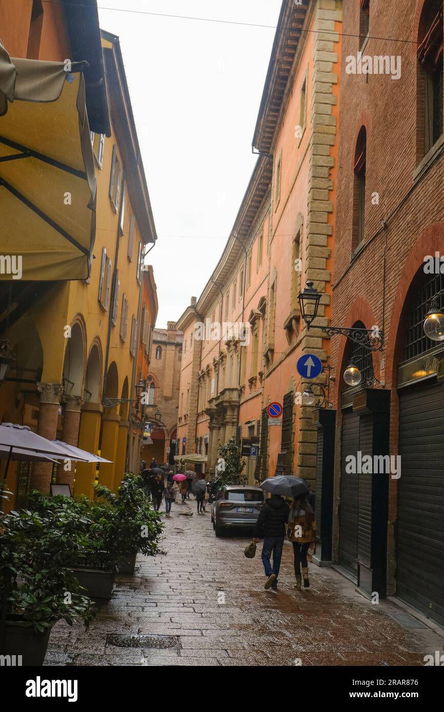 Maggio 2023 Bologna, Italia: Le strette stradine della città vecchia durante la pioggia. Persone che visitano la città con ombrelloni Foto Stock
