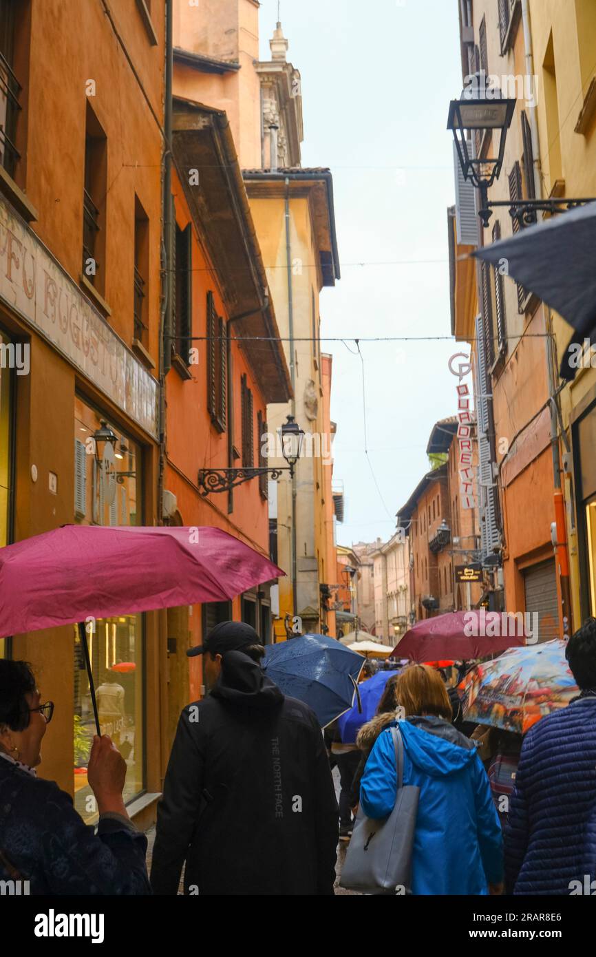 Maggio 2023 Bologna, Italia: Le strette stradine della città vecchia durante la pioggia. Persone che visitano la città con ombrelloni Foto Stock