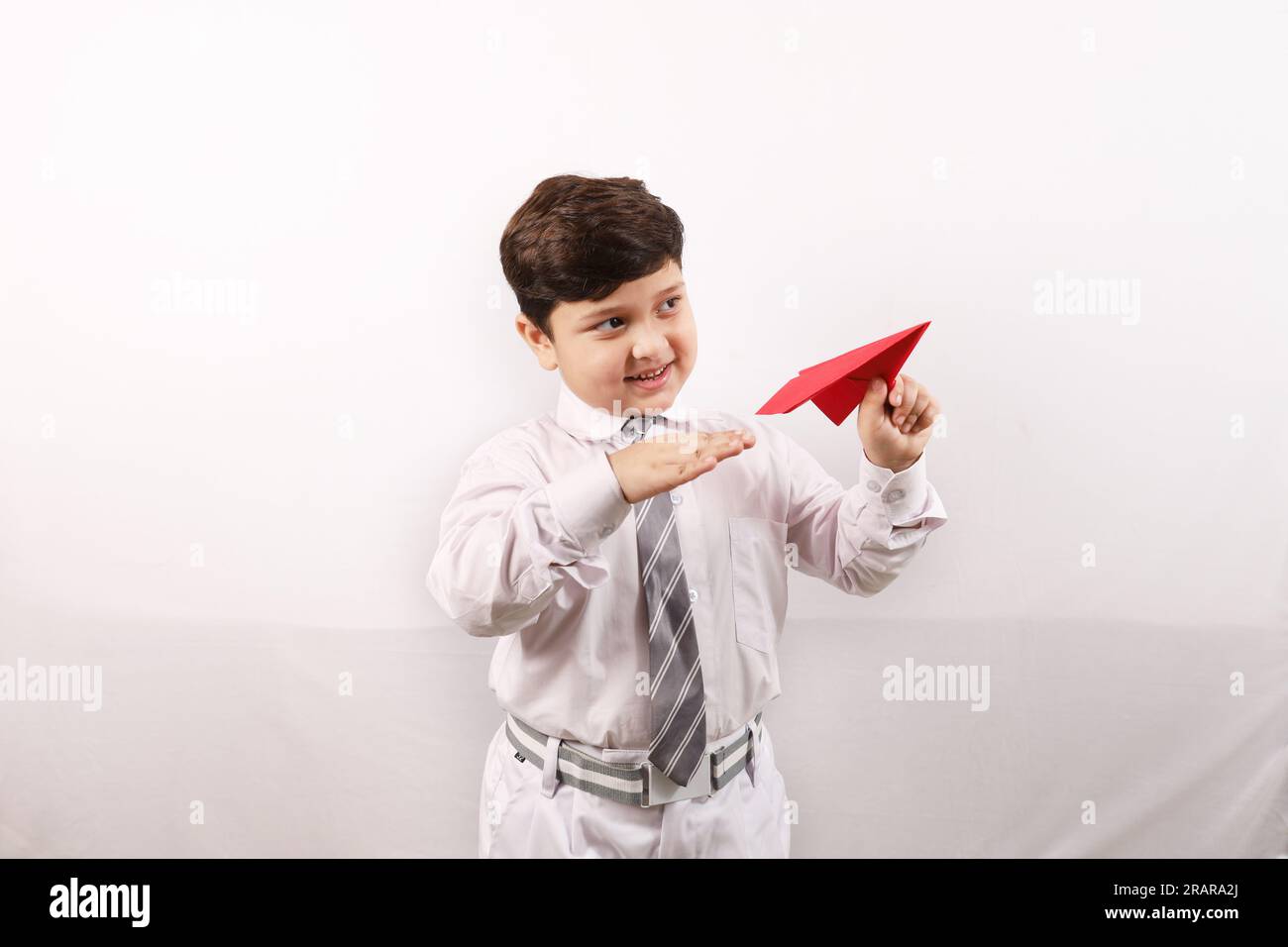 Un ragazzo indiano felice che gioca con un aereo di carta e sogna di raggiungere altezze e raggiungere obiettivi e traguardi. Hostess di aria o pilota. Foto Stock