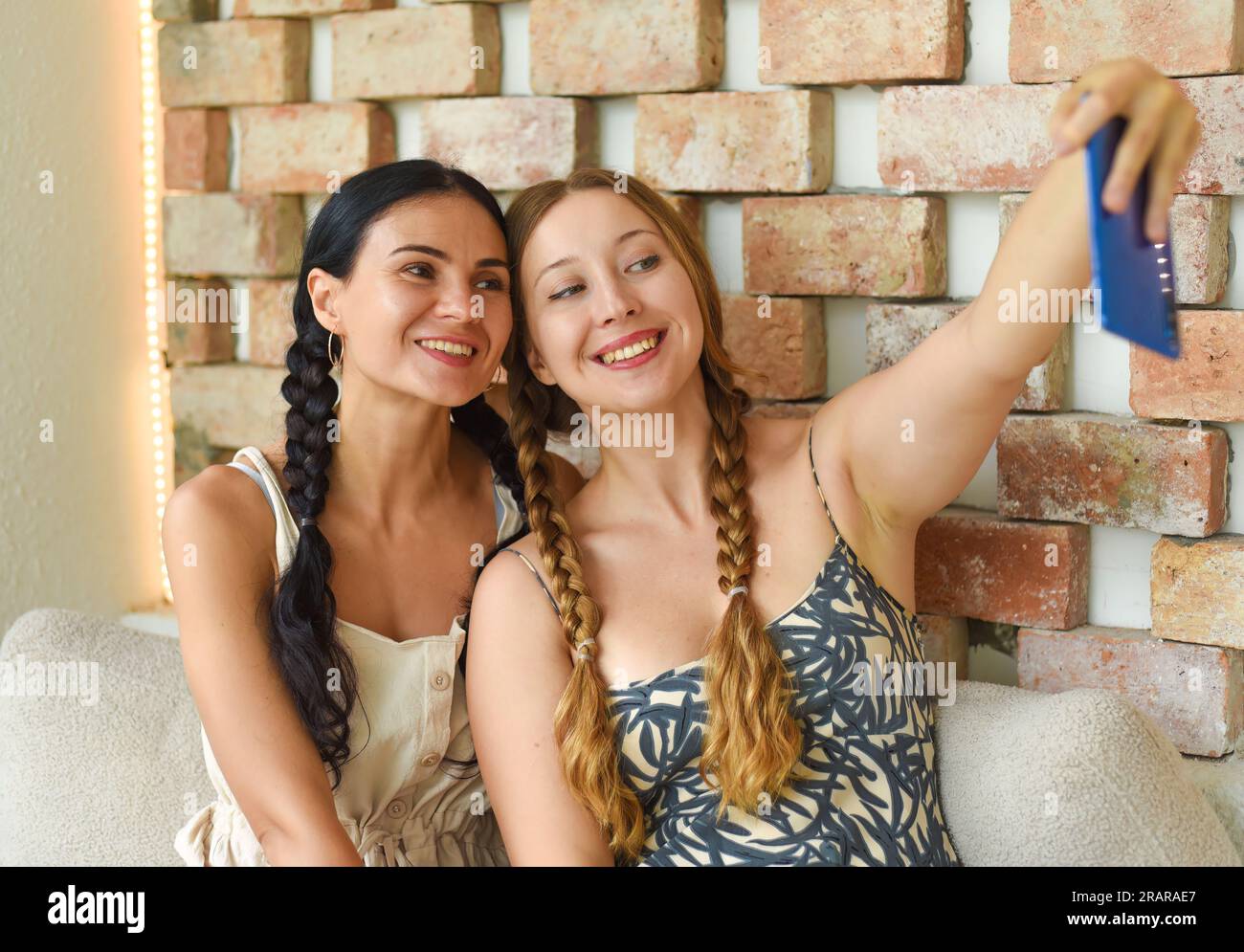 Ritratto di donna Ucraina (bruna) e donna russa (bionda) insieme a trecce che posa e scatta un selfie Foto Stock