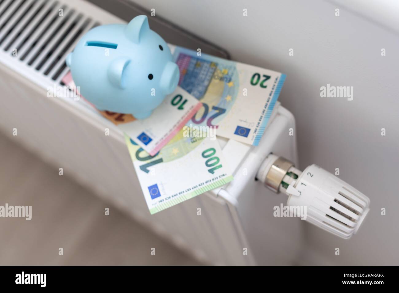 Porcellino piggy banca e dollari fatture su un radiatore al chiuso-up. Concetto di riscaldamento. Foto Stock