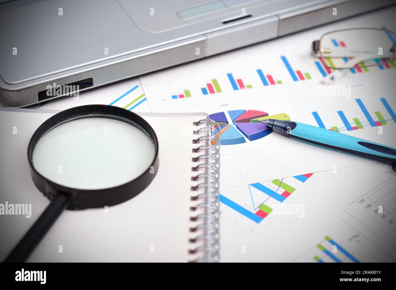 concetto di analisi di mercato con report finanziario, penna, laptop e lente d'ingrandimento Foto Stock