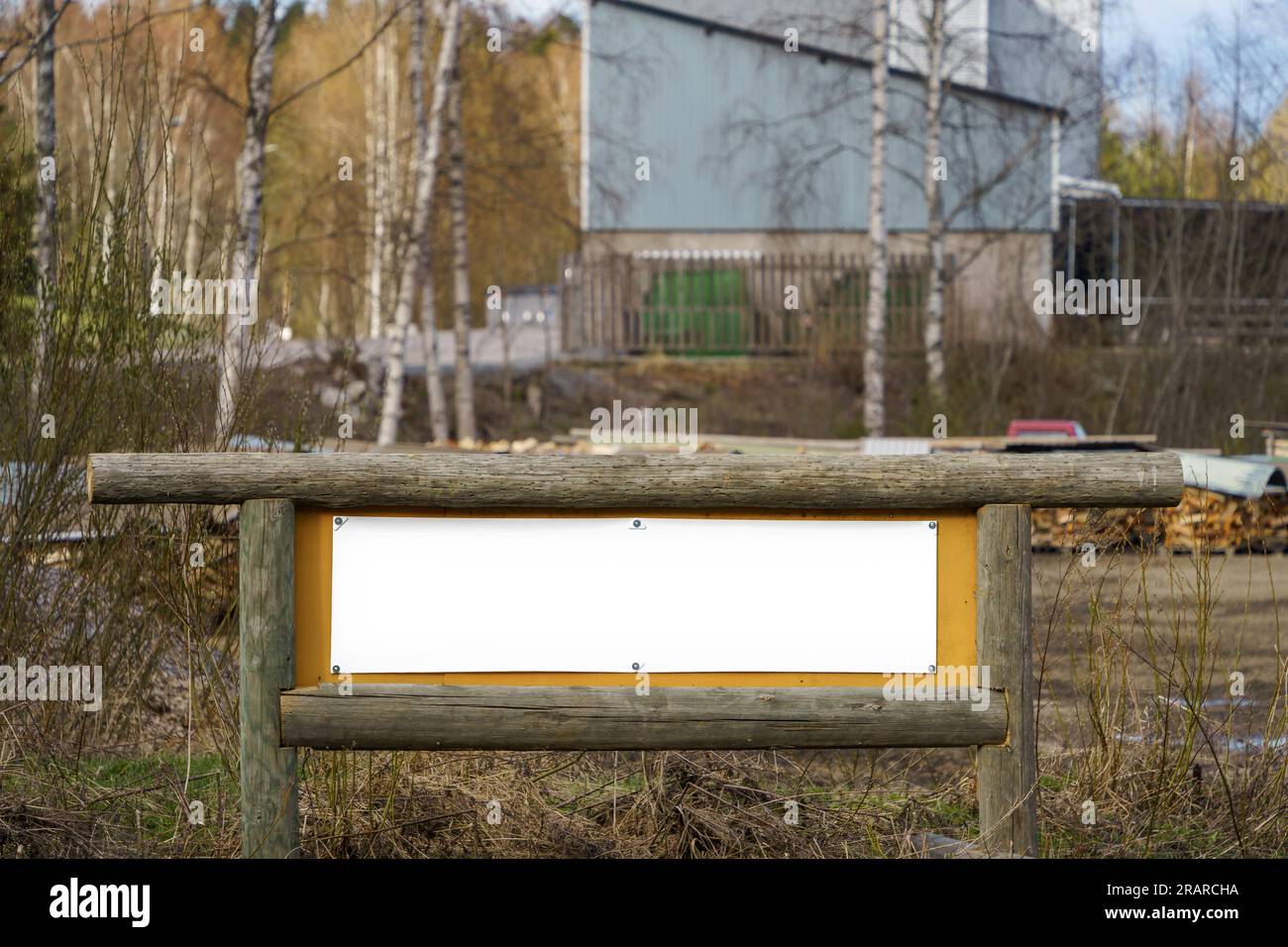 Cartello bianco vuoto con telaio in legno. Zona industriale in campagna Finlandia. Foto Stock