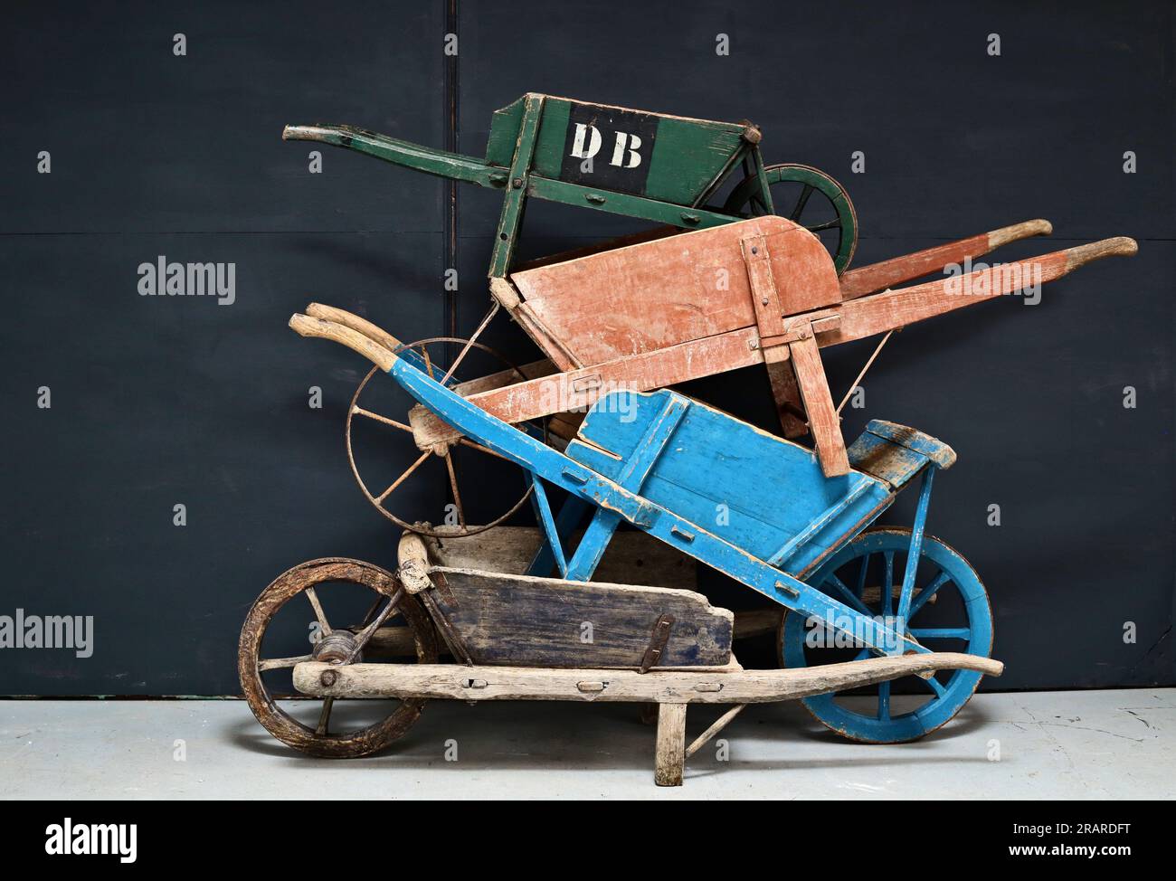 Le carriole in legno d'epoca sovrapposte sono esposte in una disposizione colorata su sfondo scuro Foto Stock