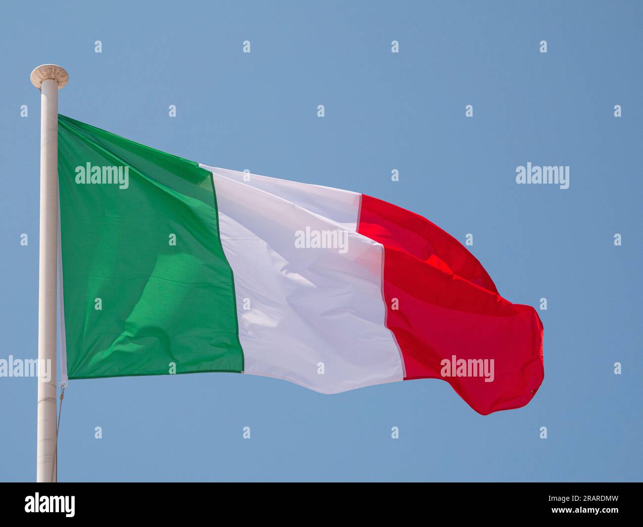 Italia la bandiera nazionale italiana che sventola al vento su un palo con sfondo blu. Foto Stock