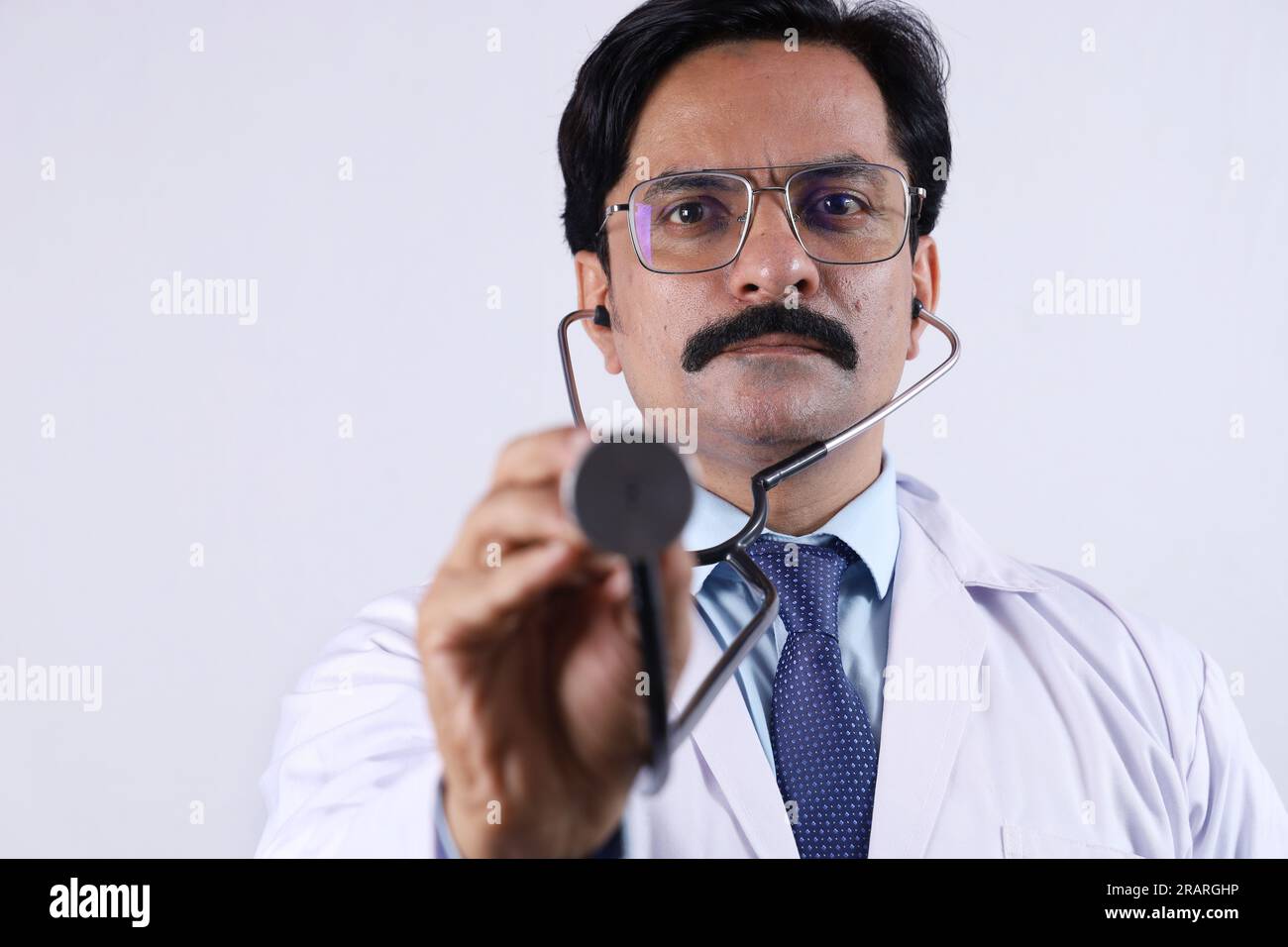 Ritratto di un medico indiano felice in uniforme che mostra stetoscopio e specifiche. Stetoscopio. Dottore in baffi. Medico e sanitario. Foto Stock