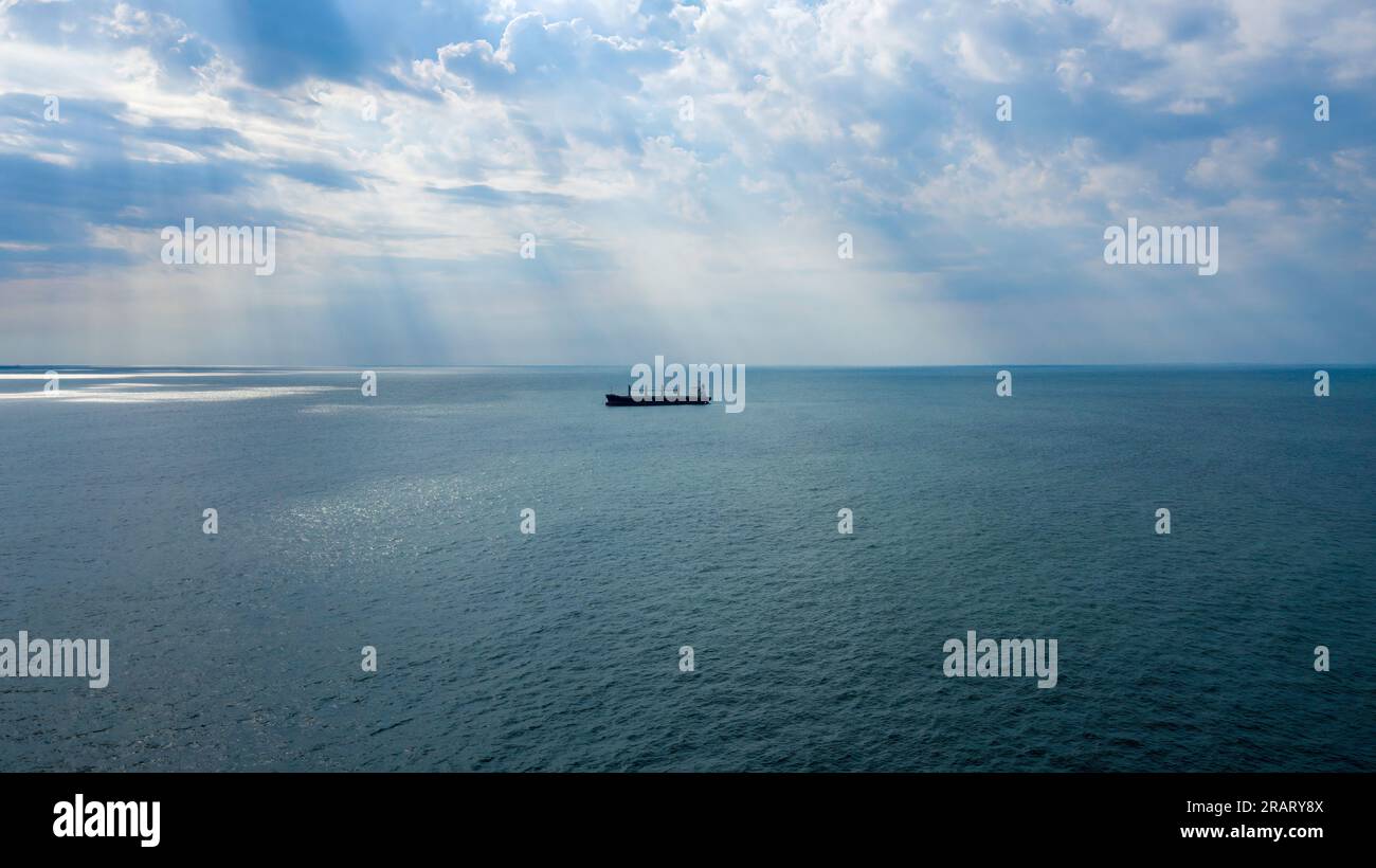 Portarinfuse autoscaricante presso l'ancoraggio Rio De la Plata. I raggi del sole brillano attraverso le nuvole. Visuale ampia dell'antenna. Foto Stock