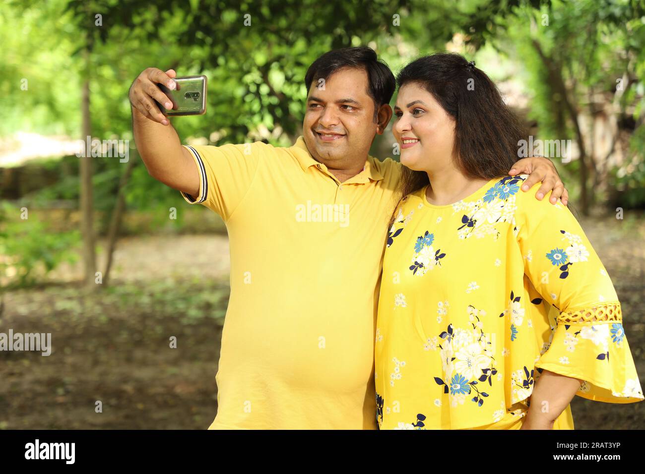 Felice giovane bella coppia indiana in piedi insieme sul sentiero, scattando selfie con il loro cellulare. Foto Stock