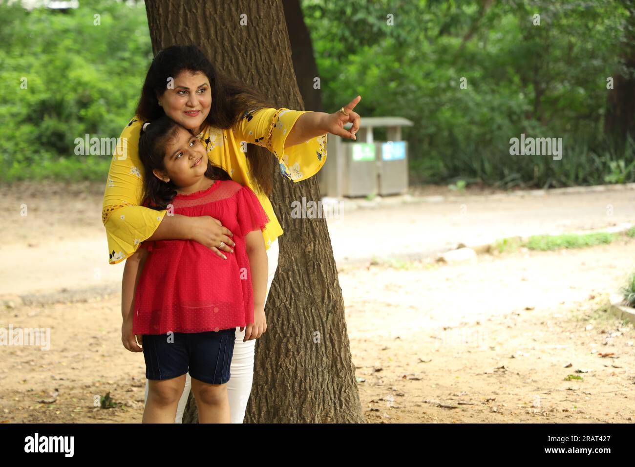 Madre e figlia felici che si divertono insieme in un parco pubblico. madre single che gioca con sua figlia in un'atmosfera verde e pulita. Foto Stock