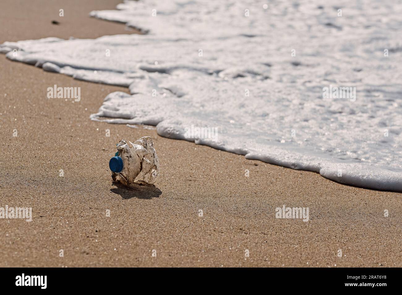 Una bottiglia di plastica si trova sulla spiaggia sabbiosa e inquina il mare e la vita marina. Il concetto di controllo dell'inquinamento dei mari e degli oceani Foto Stock