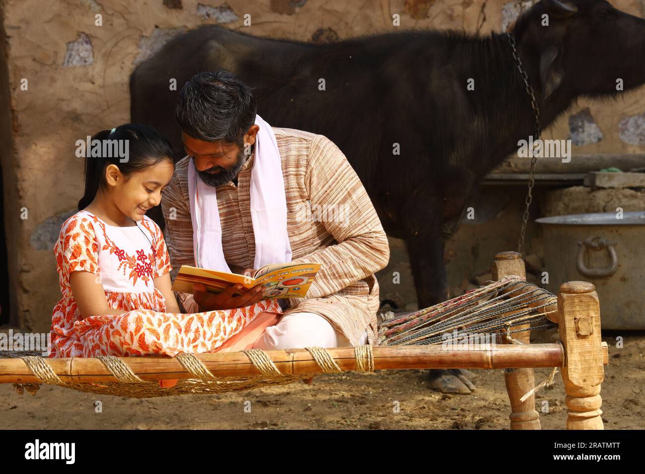 Padre e figlia rurale indiani che studiano il libro insieme. L'educazione infantile raggiunge tutti i villaggi dell'India. Gli agricoltori sono consapevoli di insegnare alla loro figlia. Foto Stock