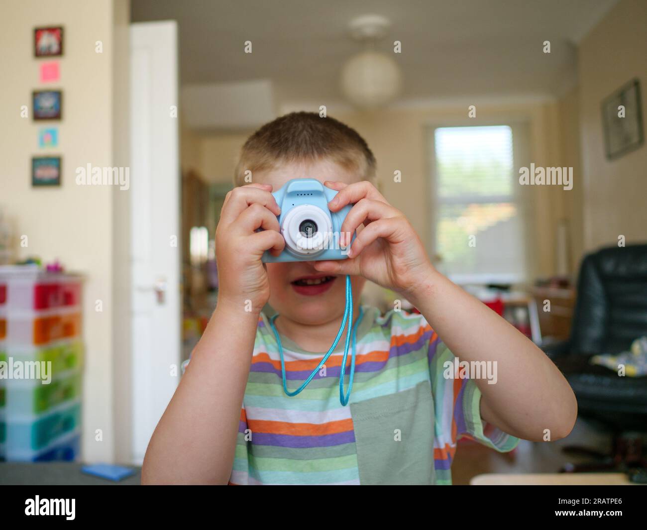 Bambino di quattro anni che scatta foto con una piccola fotocamera di plastica Foto Stock