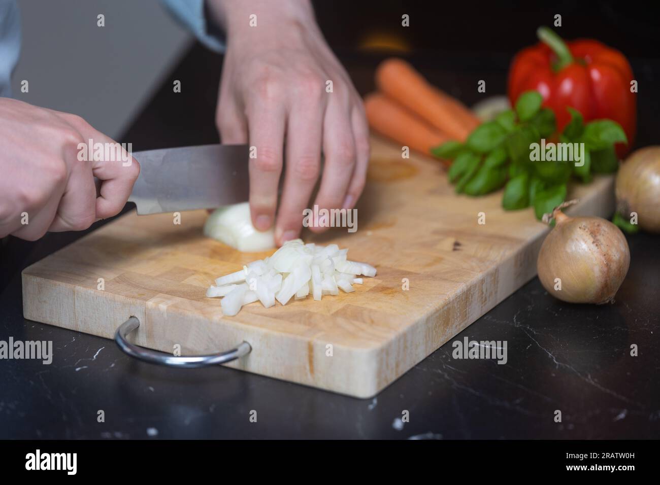 Uomo in camicia blu che taglia e taglia cipolla og tagliere di legno, con  altre verdure sullo sfondo Foto stock - Alamy