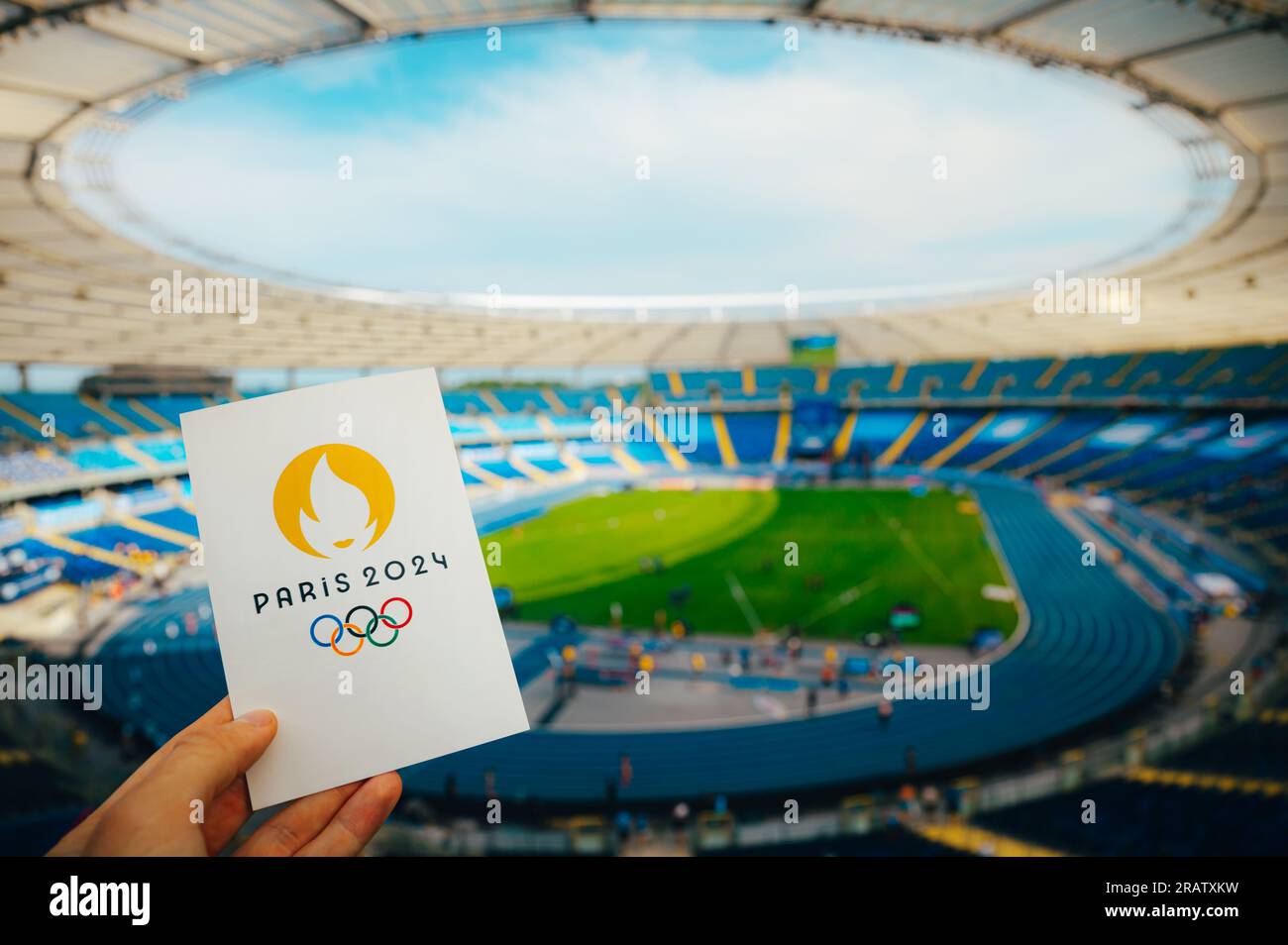 PARIGI, FRANCIA, 7 LUGLIO 2023: Icona dei Giochi olimpici estivi Parigi 2024 tenuta dall'atleta. Moderno Stadio Olimpico sullo sfondo. Sfondo per Summer Olymp Foto Stock