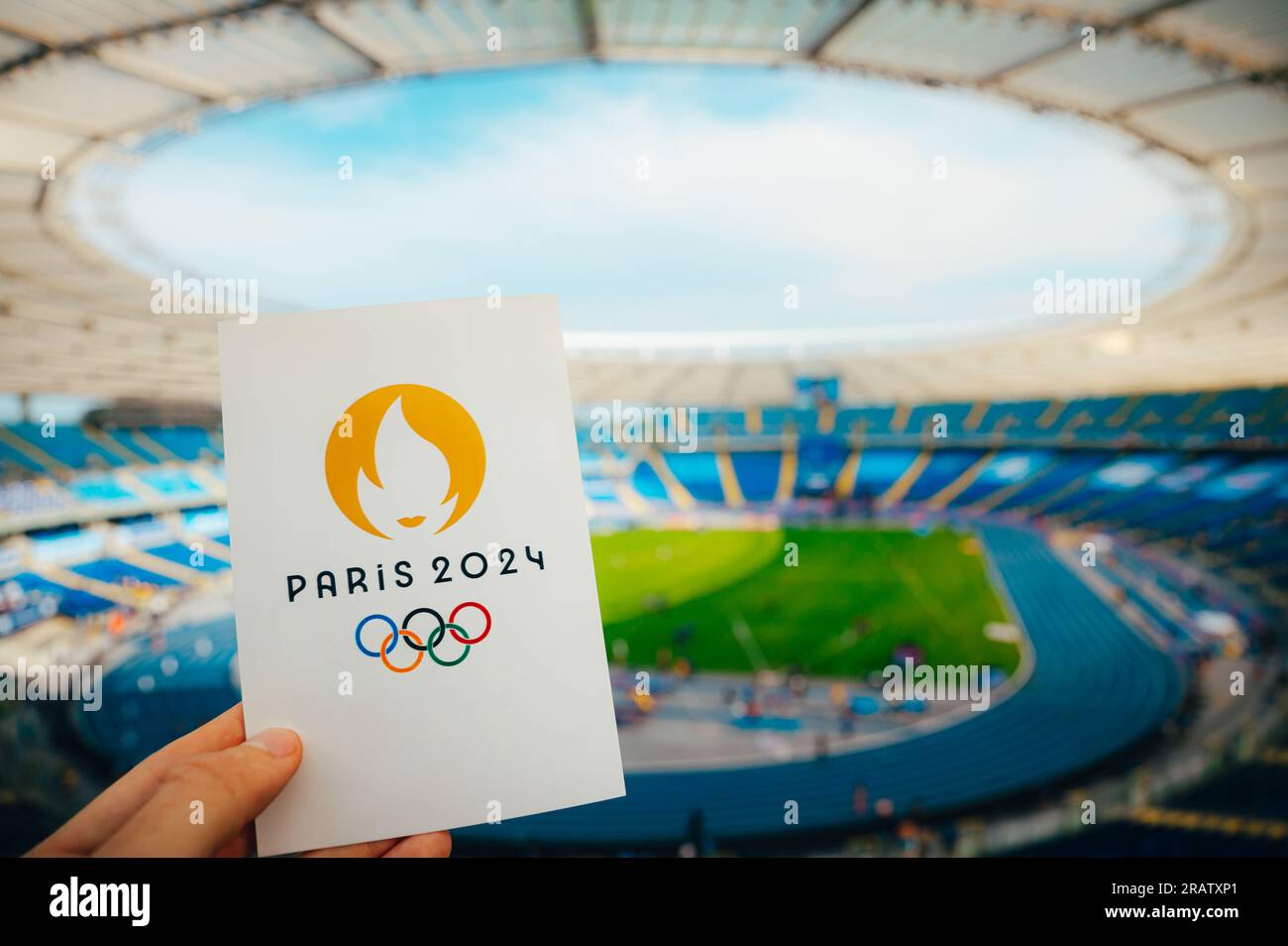 PARIGI, FRANCIA, 7 LUGLIO 2023: Icona dei Giochi olimpici estivi Parigi 2024 tenuta dall'atleta. Moderno Stadio Olimpico sullo sfondo. Sfondo per Summer Olymp Foto Stock