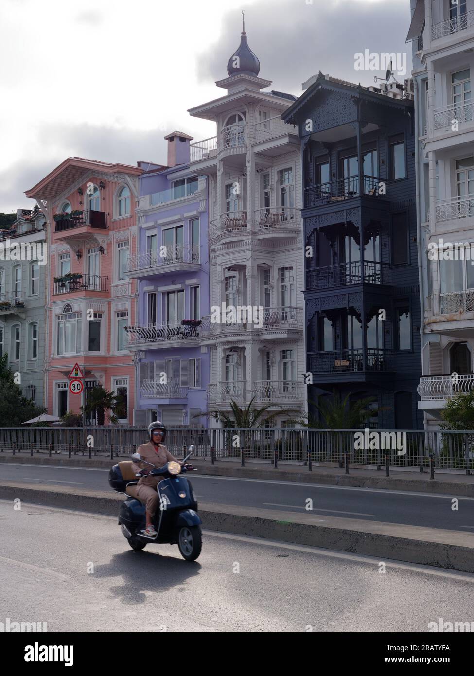 Motociclista di fronte a caratteristiche proprietà in una strada nel quartiere di Bebek, Istanbul, Turchia Foto Stock