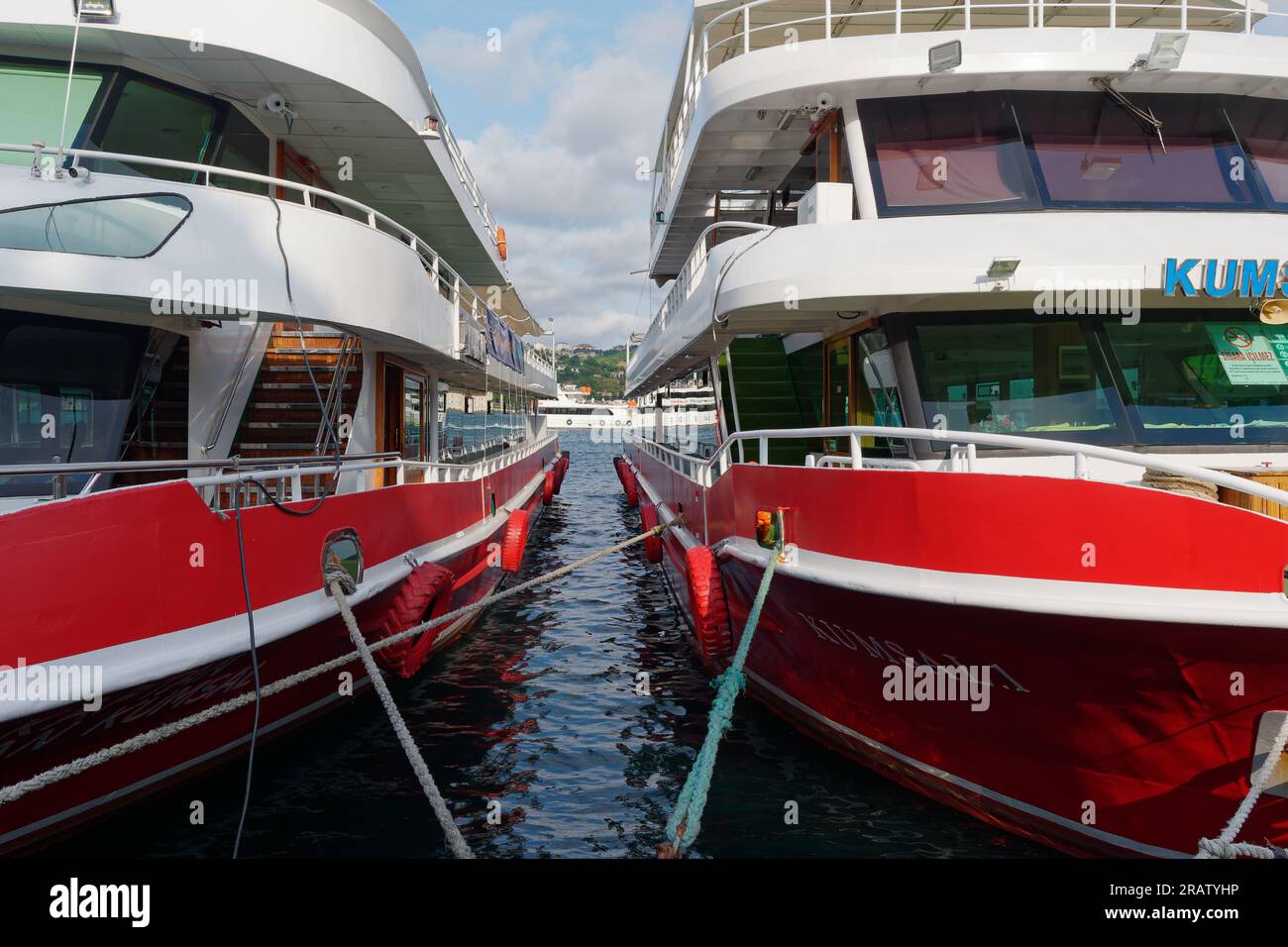 Traghetti passeggeri rossi e bianchi ormeggiati sul Mare del Bosforo a Istanbul, Turchia, mentre un'altra barca passa sullo sfondo. Foto Stock