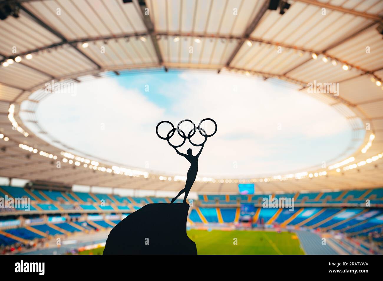 PARIGI, FRANCIA, 7 LUGLIO 2023: Harmony of Athletics: Statue of Athlete abbraccia il cerchio Olimpico contro il moderno Stadio Olimpico. Una foto sportiva per Parigi 2 Foto Stock