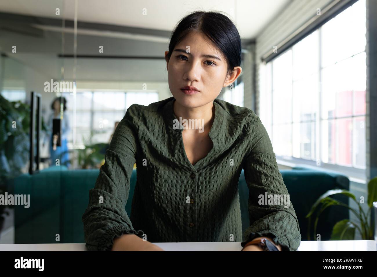 Donna d'affari asiatica informale che fa videochiamate e gesti seduti alla scrivania in ufficio. Lavoro, affari, comunicazione e ufficio informale, inalterato Foto Stock