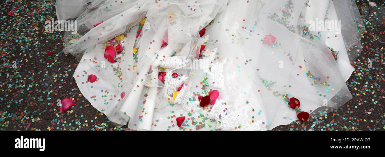Traine de robe blanche de mariée au sol avec petales de fleurs et confettis format panoramique Foto Stock