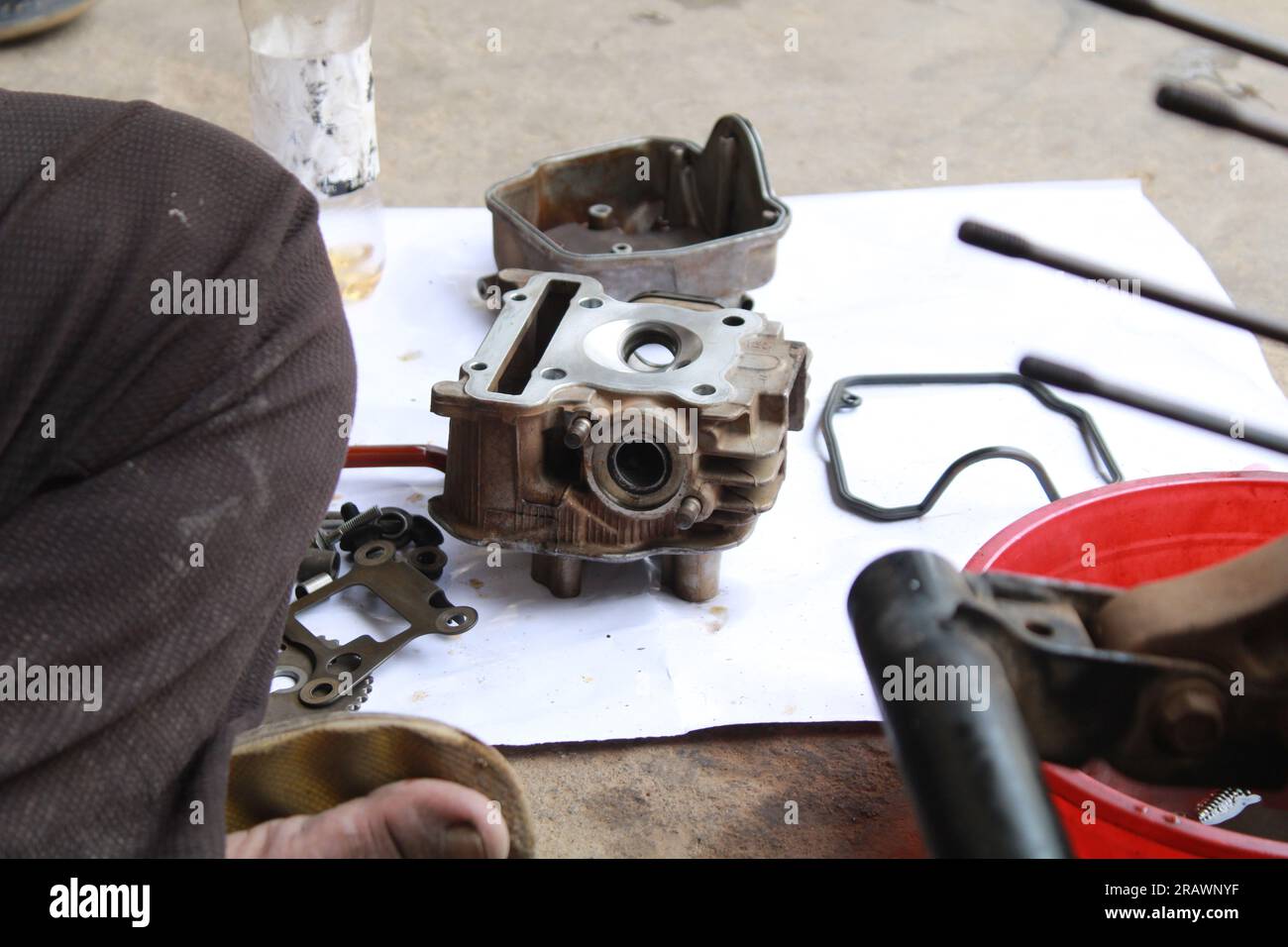 Il meccanico ripara un ciclomotore. Un uomo lavora come meccanico in un'officina di riparazione motociclistica locale. Odisha, India. Foto Stock