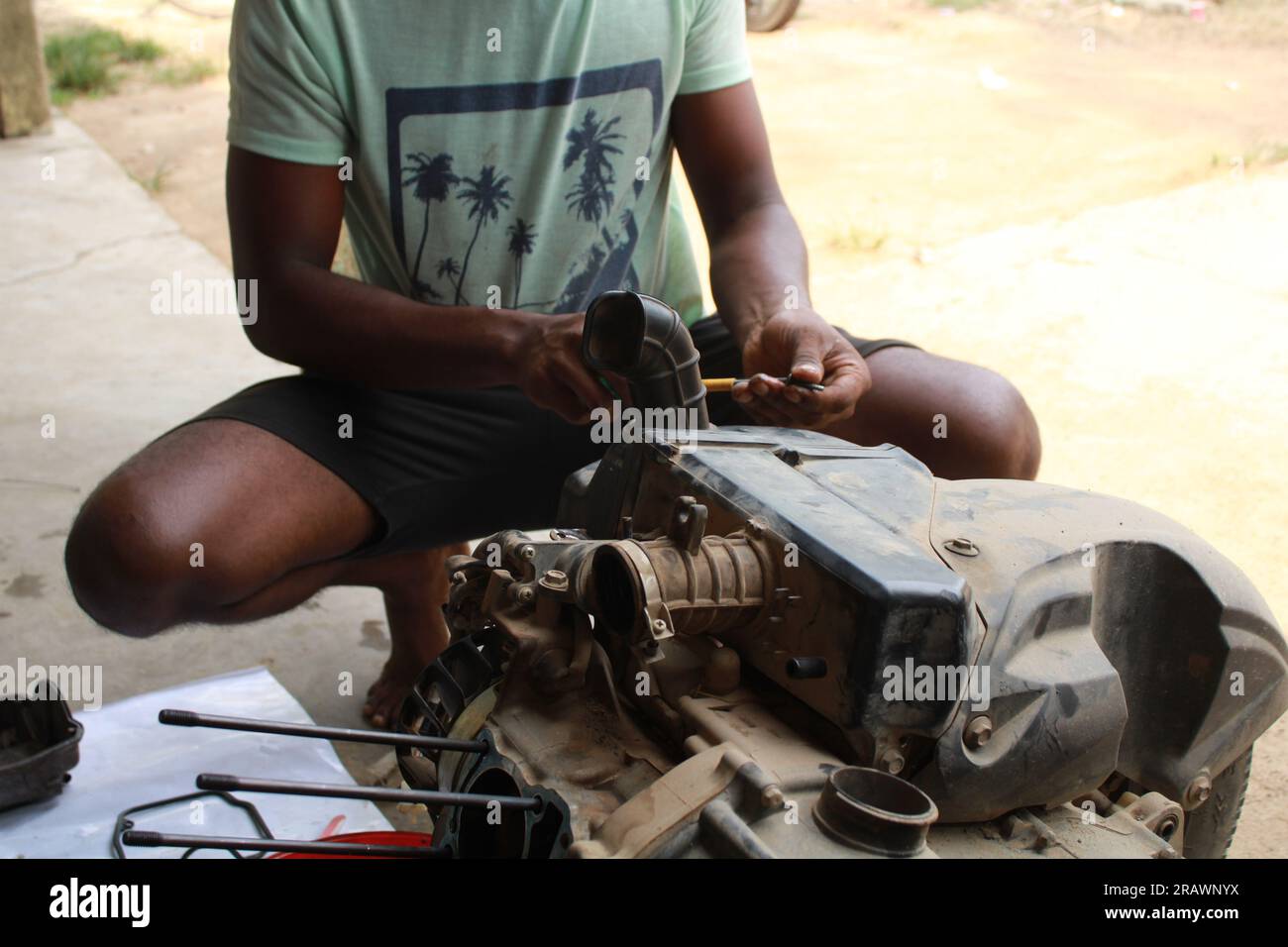 Il meccanico ripara un ciclomotore. Un uomo lavora come meccanico in un'officina di riparazione motociclistica locale. Odisha, India. Foto Stock