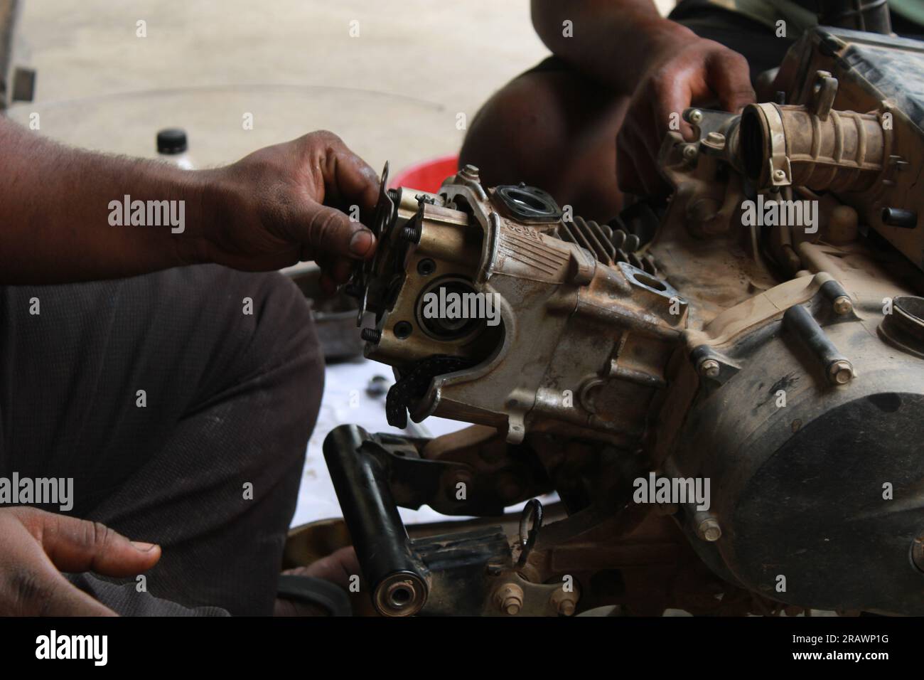 Il meccanico ripara un ciclomotore. Un uomo lavora come meccanico in un'officina di riparazione motociclistica locale. Odisha, India. Foto Stock